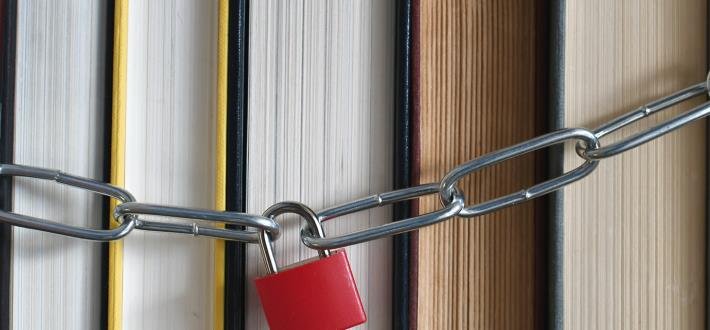 Five books with page side visible chained together with a padlock