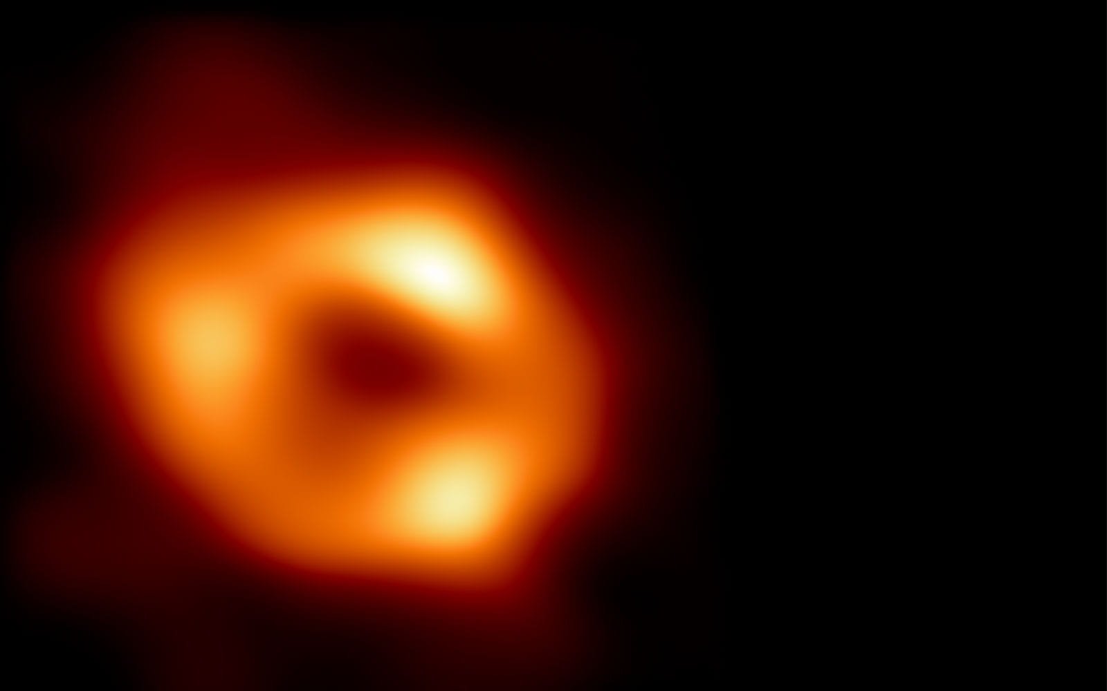 Telescopic image of a black hole, a glowing orange ring against a dark background